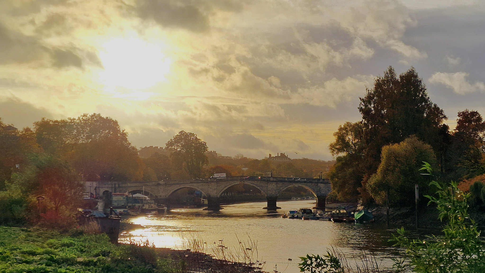 A broad river flowing beneath a stone bridge in warm evening light